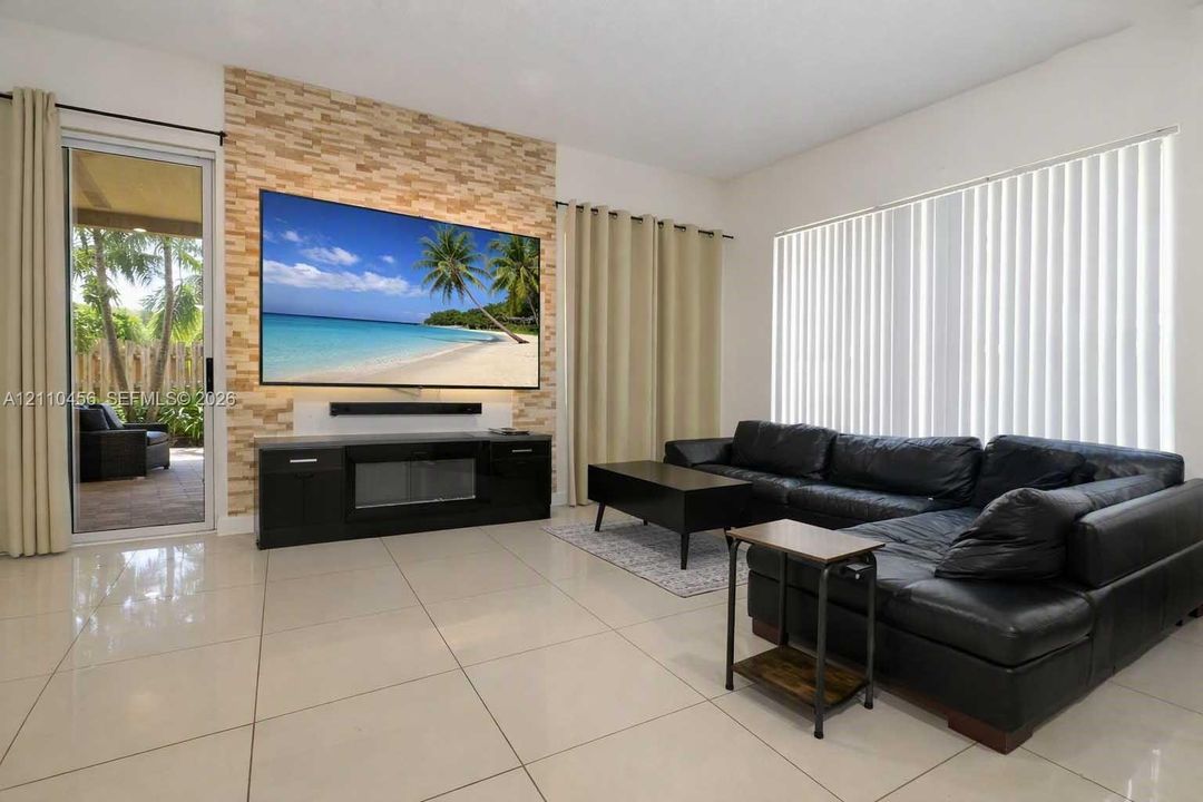 Stacked stone accent wall featuring a built-in media console with an integrated fireplace and large-format tile flooring
