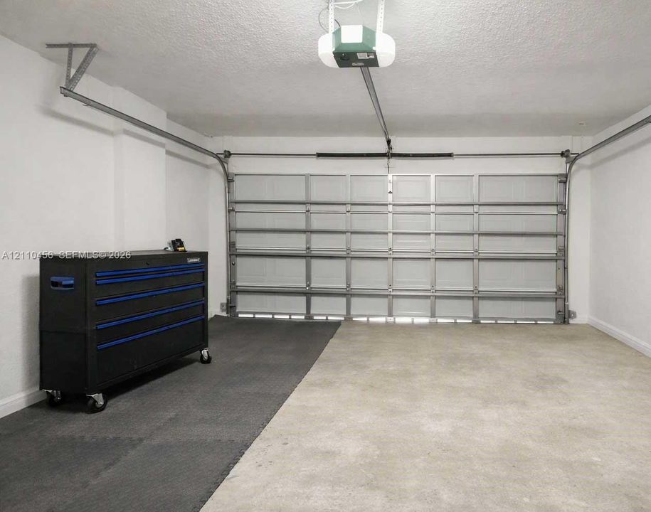Two-car garage featuring a sectional metal door, concrete flooring, and an automated garage door opener