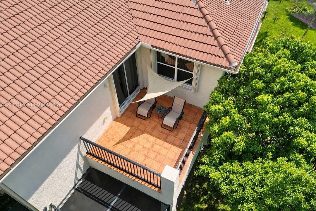 Second-story balcony featuring terracotta tile flooring, black metal railing, and a terracotta-tiled roof