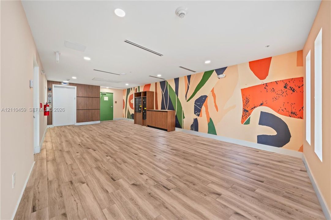 Common area featuring wood-finish flooring, a vibrant mural wall, recessed ceiling lighting, a built-in mail station, and wood-paneled accents