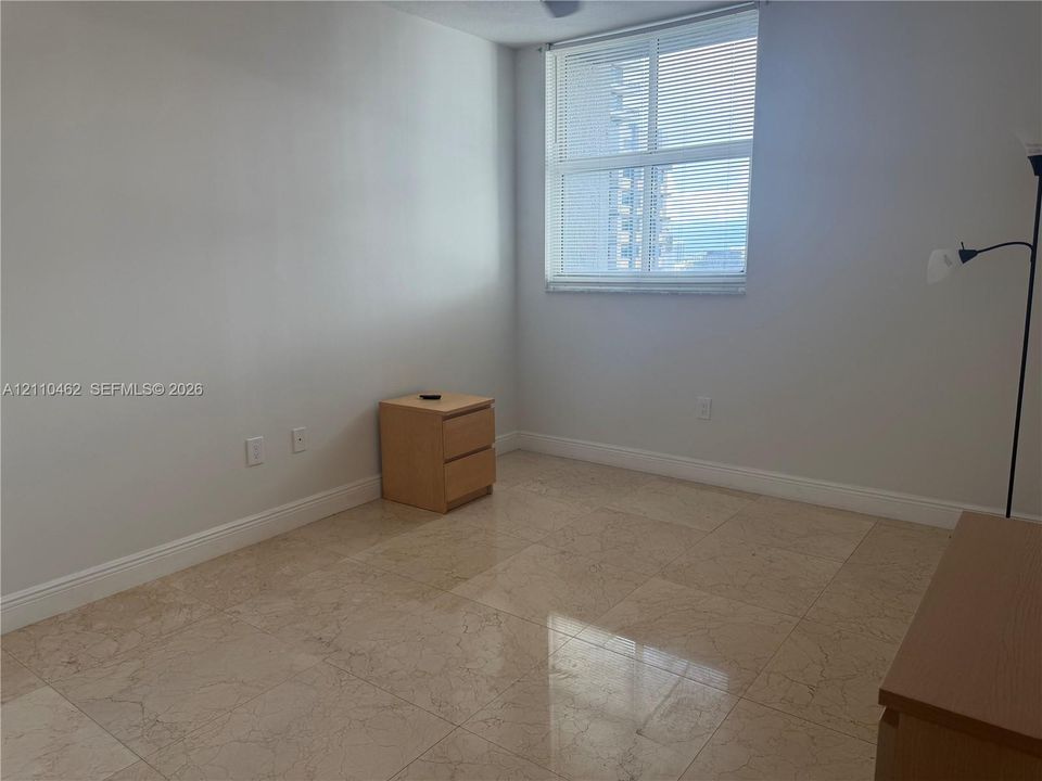 Large room featuring stone tile flooring and a prominent window with horizontal blinds
