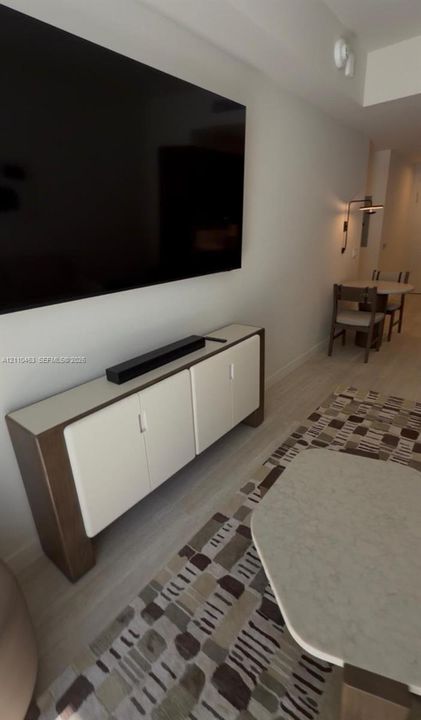 Built-in cabinetry featuring white doors and a complementary countertop, complemented by light-toned wood-finish flooring and a wall-mounted light fixture