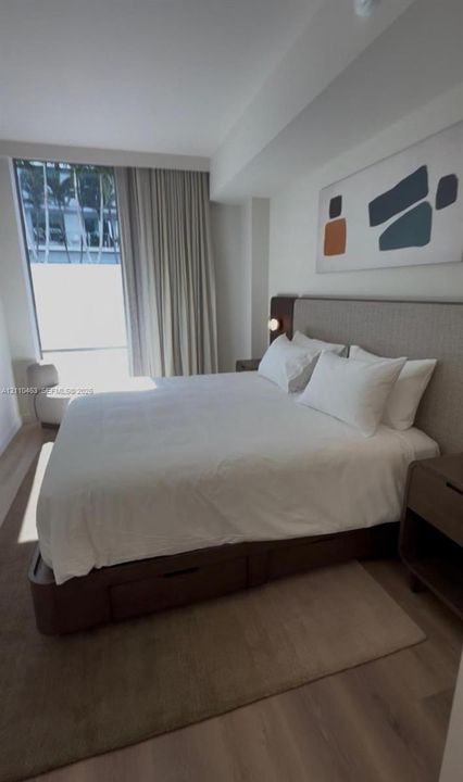 Floor-to-ceiling windows with integrated drapery and wood-finish flooring