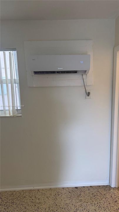 Wall-mounted ductless mini-split climate control system, vertical slat window blinds, and aggregate flooring