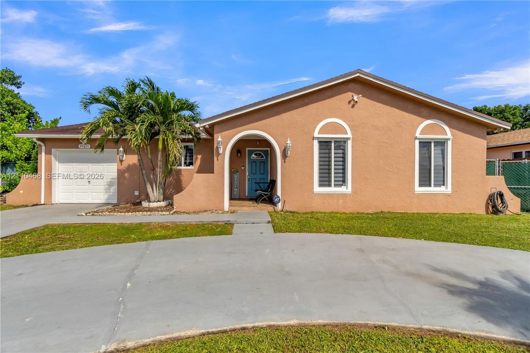Stucco exterior featuring an arched entryway, single-car garage, concrete driveway, and window accents with arched detailing