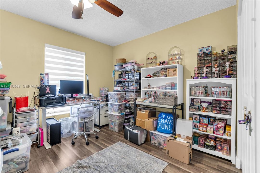 Wood-finish flooring, ceiling fan with light fixture, and large window with blinds