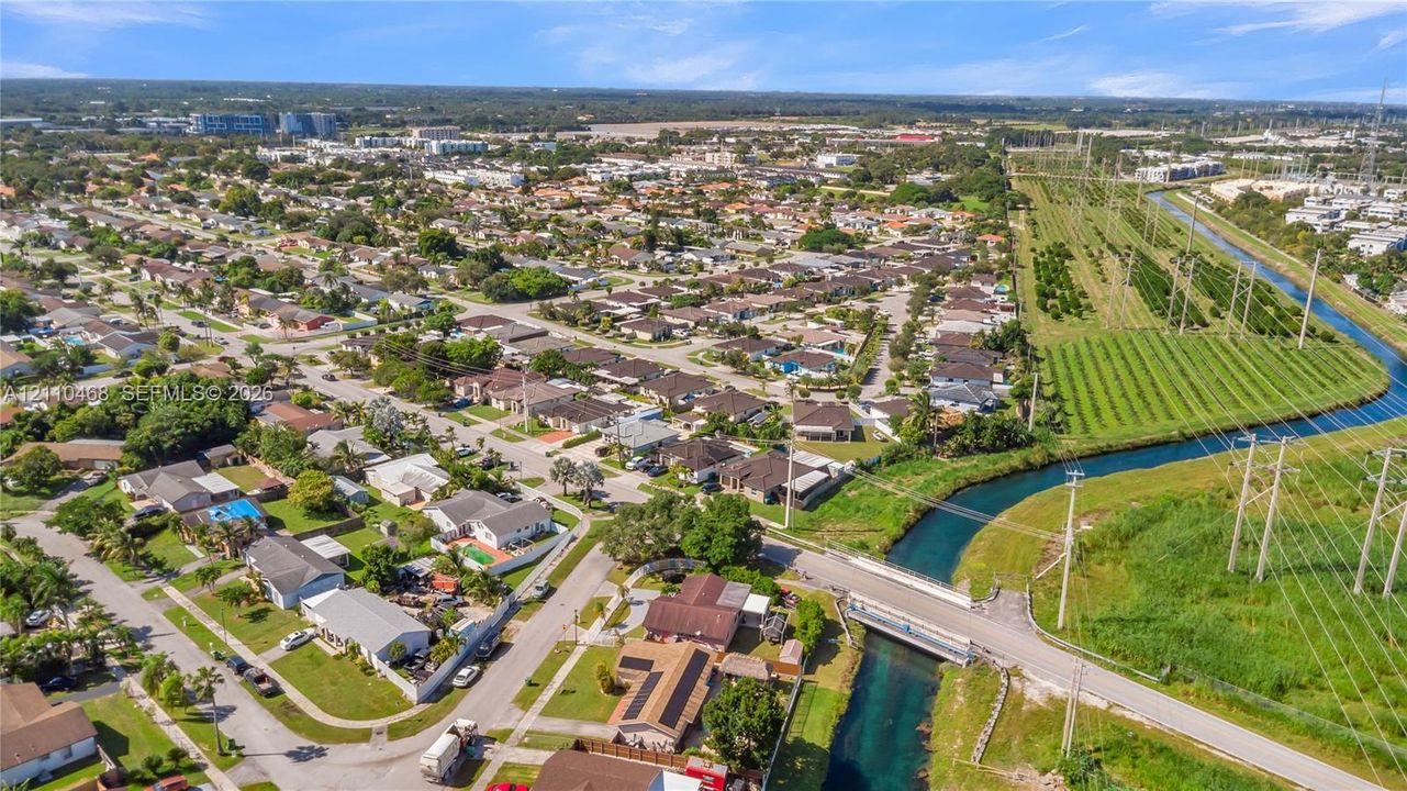 Aerial perspective featuring a suburban residential grid, waterway corridor, and expansive green space