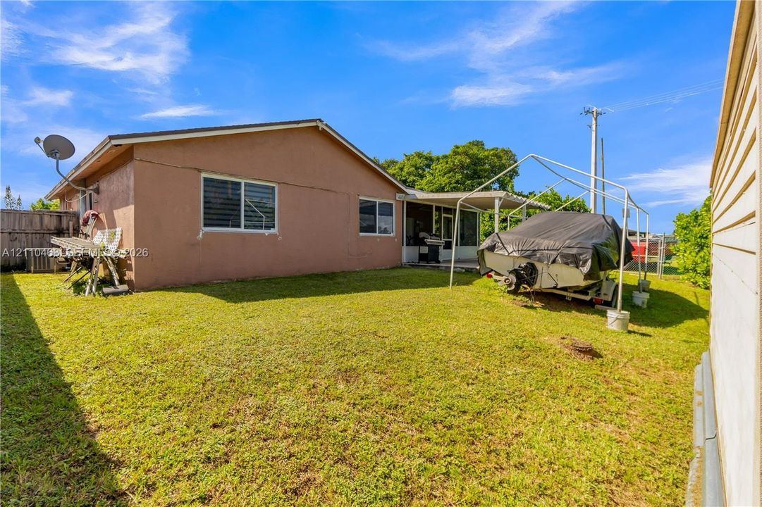 Exterior of the property featuring a rear lawn, stucco siding, horizontal sliding windows, and a covered rear patio area