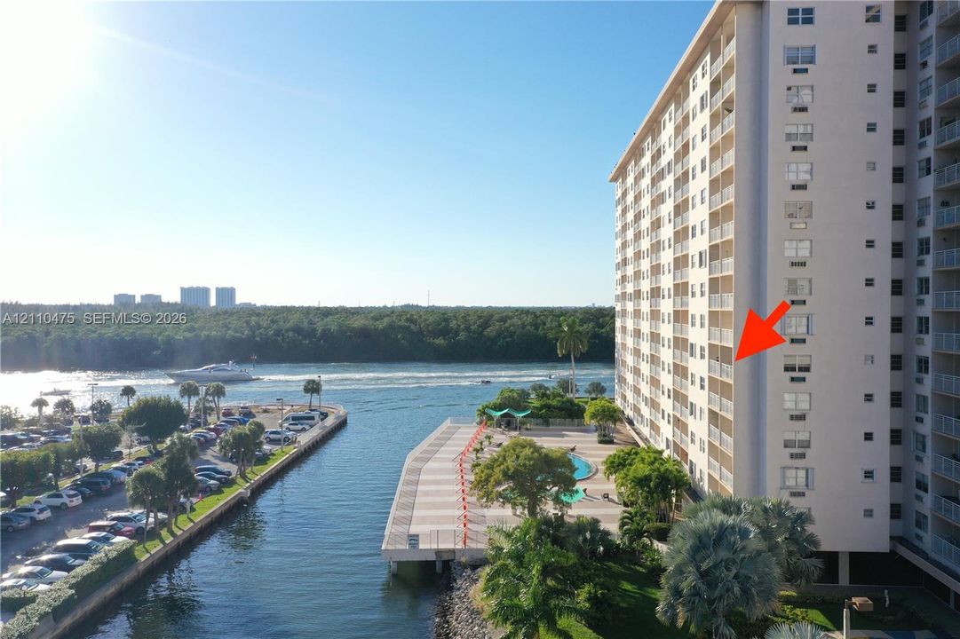 High-rise building featuring private balconies, an outdoor swimming pool, paved waterfront deck, and direct access to the waterway