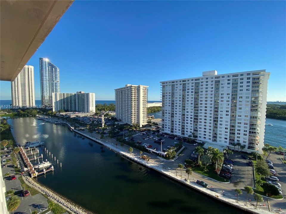 Aerial perspective featuring a waterfront setting with a private boat dock, concrete bulkhead, and surrounding coastal high-rise structures