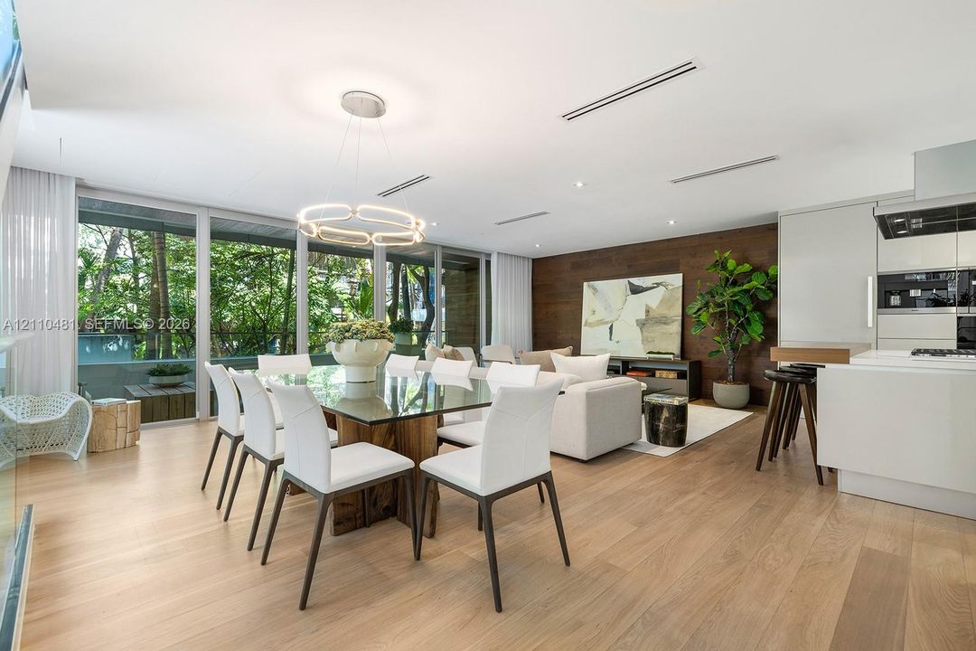 Open-concept living space featuring wood-finish flooring, floor-to-ceiling windows, a wood-paneled accent wall, and recessed linear lighting