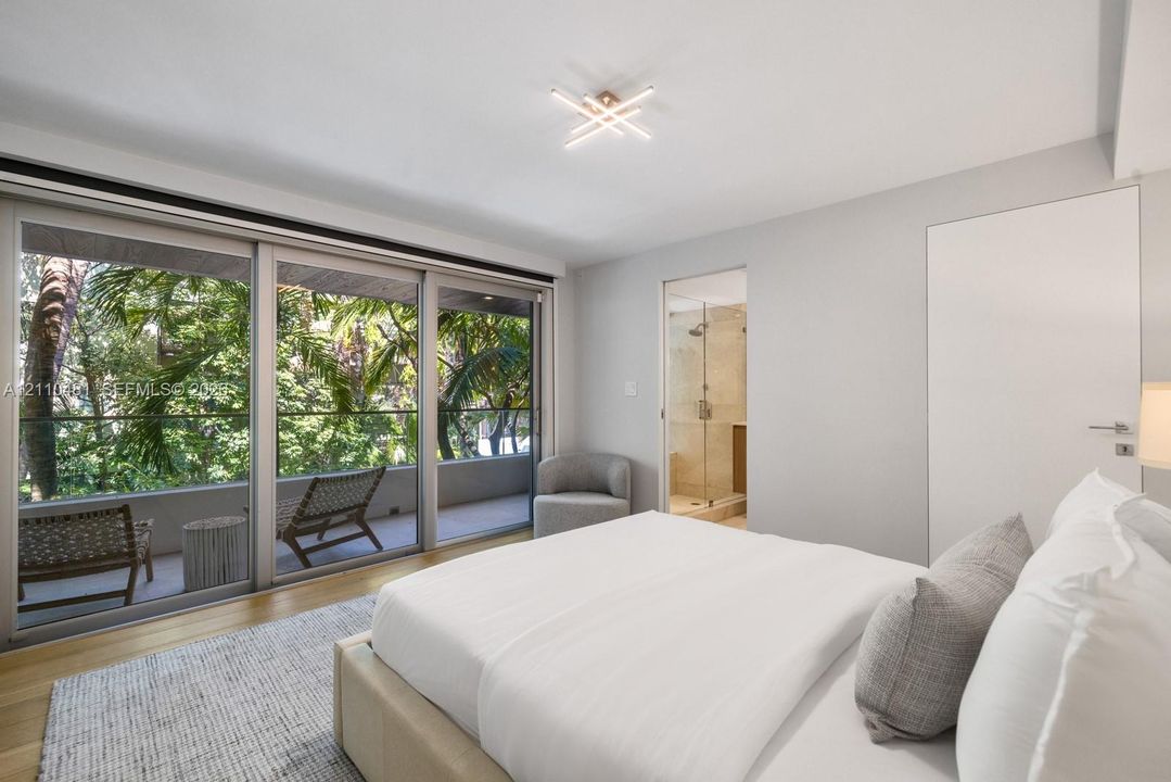 Floor-to-ceiling sliding glass doors, wood-finish flooring, recessed modern geometric lighting, and an attached balcony with a glass railing