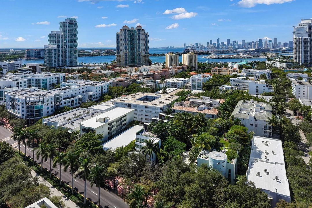 Aerial perspective featuring dense mature tree canopy, proximity to the coastline, and a panoramic skyline backdrop