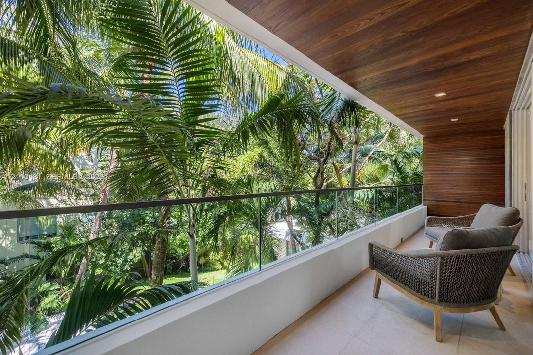 Covered balcony featuring wood-paneled ceiling, glass panel railing, and stone tile flooring