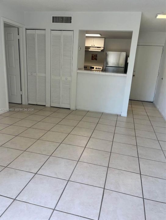 Tile flooring, dual bifold closet doors, and pass-through kitchen counter featuring stainless steel refrigerator and range