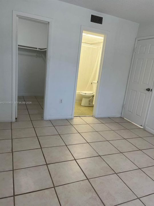 Tile flooring, six-panel interior door, and walk-in closet with built-in shelving