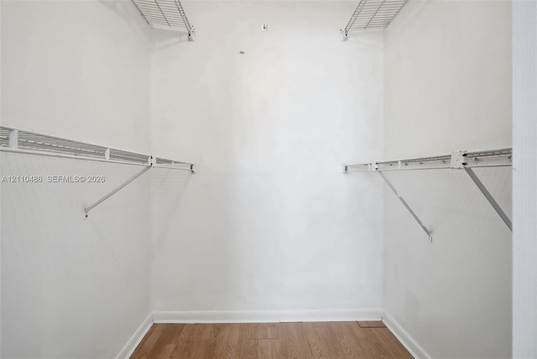 Storage area featuring wood-finish flooring and tiered white wire shelving