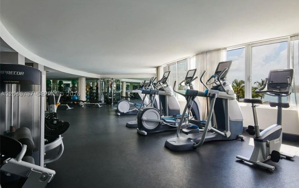 Fitness facility featuring wall-to-wall mirrors, rubberized flooring, floor-to-ceiling windows, and panoramic coastal scenery