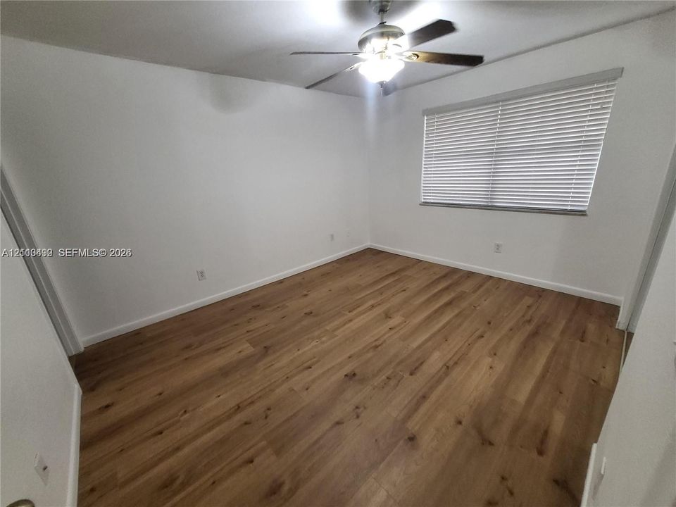 Wood-finish flooring, neutral wall tones, horizontal blinds, and a multi-blade ceiling fan with integrated lighting