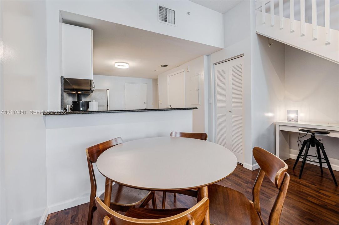 Kitchen featuring a dark stone countertop, wood-finish flooring, and a built-in staircase with white wooden railings