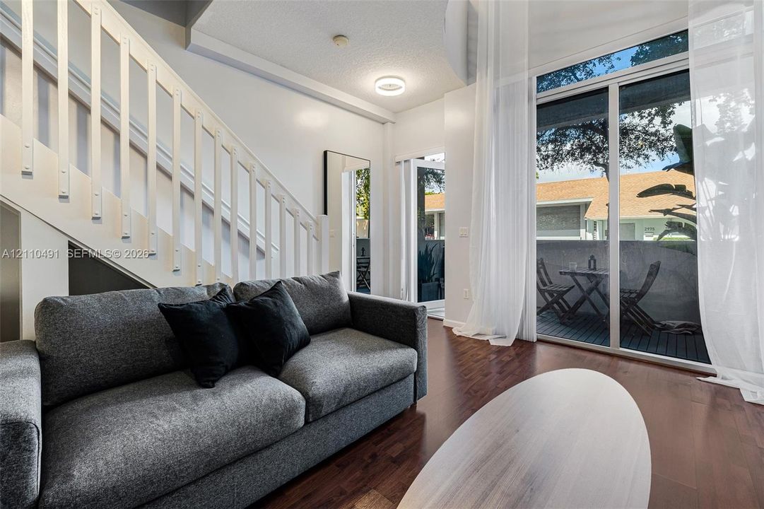 Interior space featuring wood-finish flooring, a vertical staircase with white balusters, and a floor-to-ceiling glass door providing outdoor access