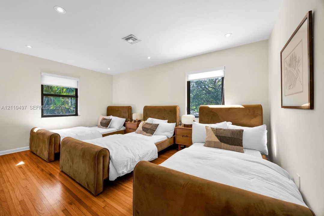 Neutral interior space featuring wood-finish flooring, recessed lighting, and multiple windows with roller shades