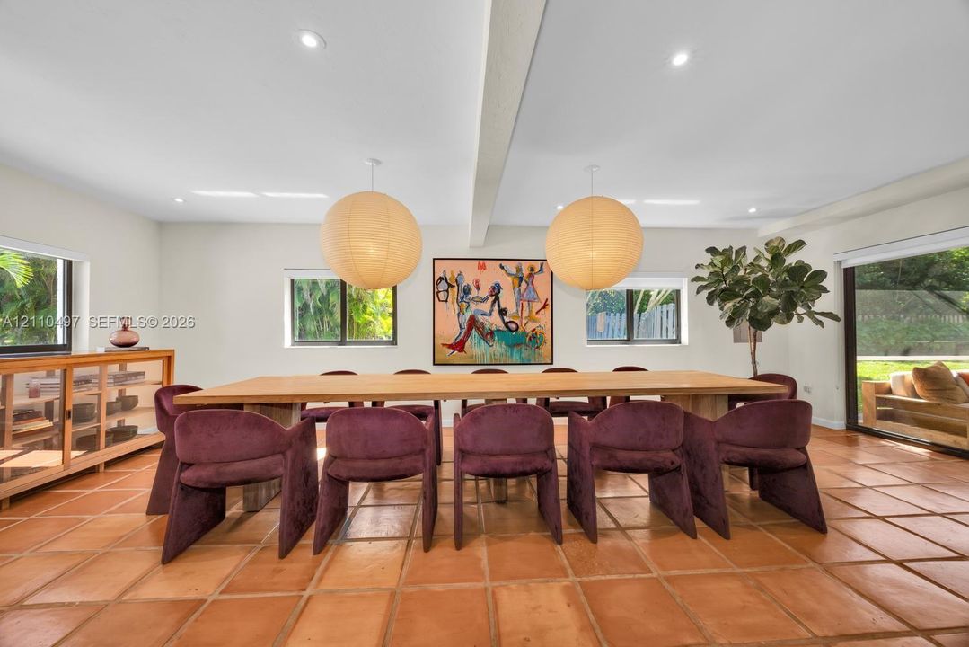 Terra cotta tile flooring, recessed ceiling lighting, oversized spherical pendant fixtures, a exposed ceiling beam, and dual sliding glass doors