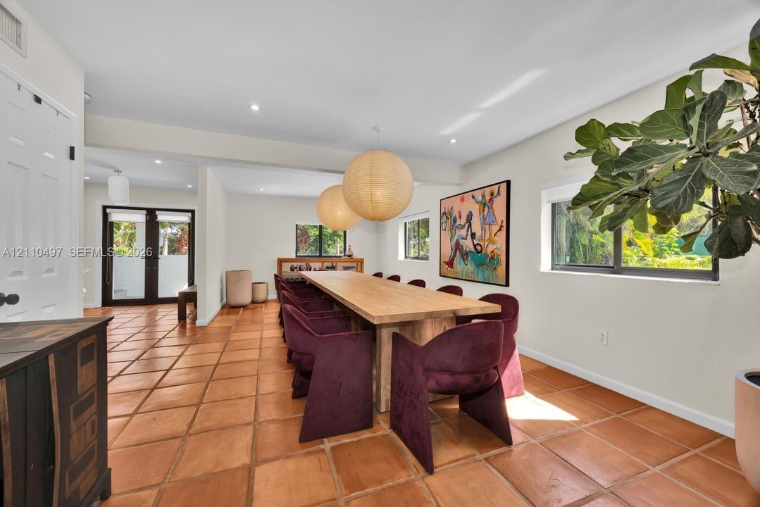 Large-format terracotta tile flooring, dual oversized spherical pendant light fixtures, and expansive windows featuring dark-framed casings