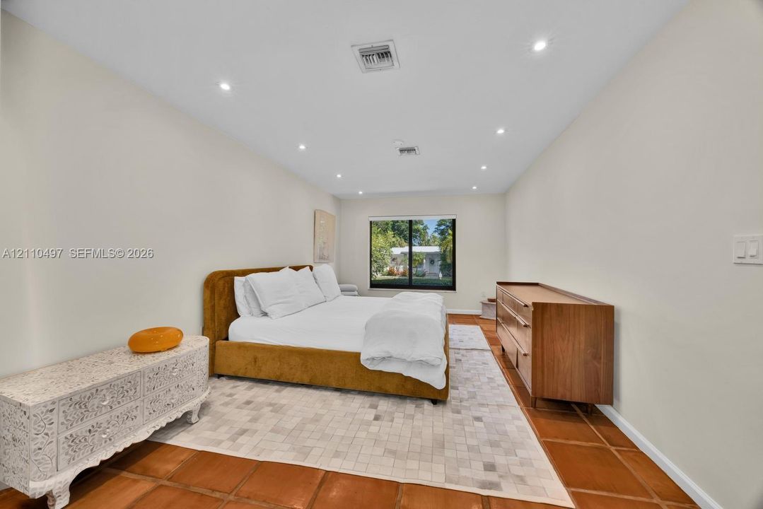 Spacious room featuring terra-cotta tile flooring, recessed ceiling lighting, and a picture window