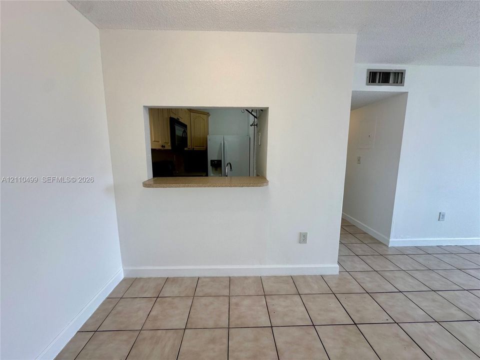 Interior space featuring ceramic tile flooring and a service pass-through opening with a countertop
