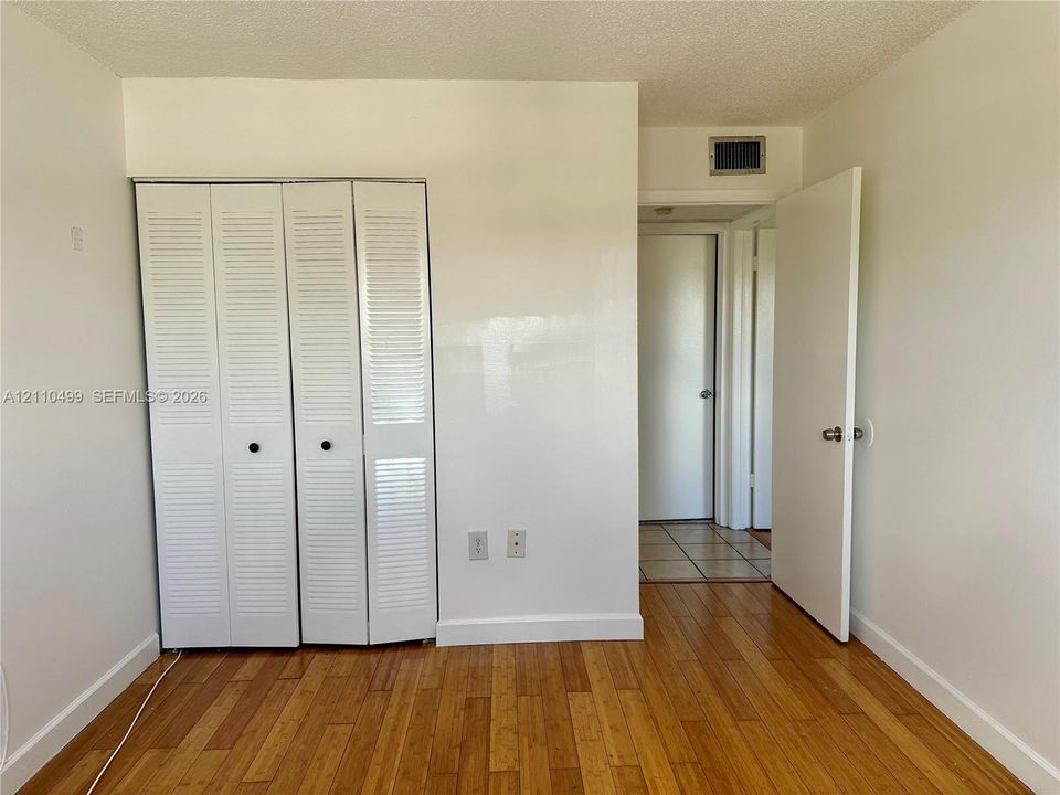 Interior space featuring wood-finish flooring and white louvered bifold closet doors