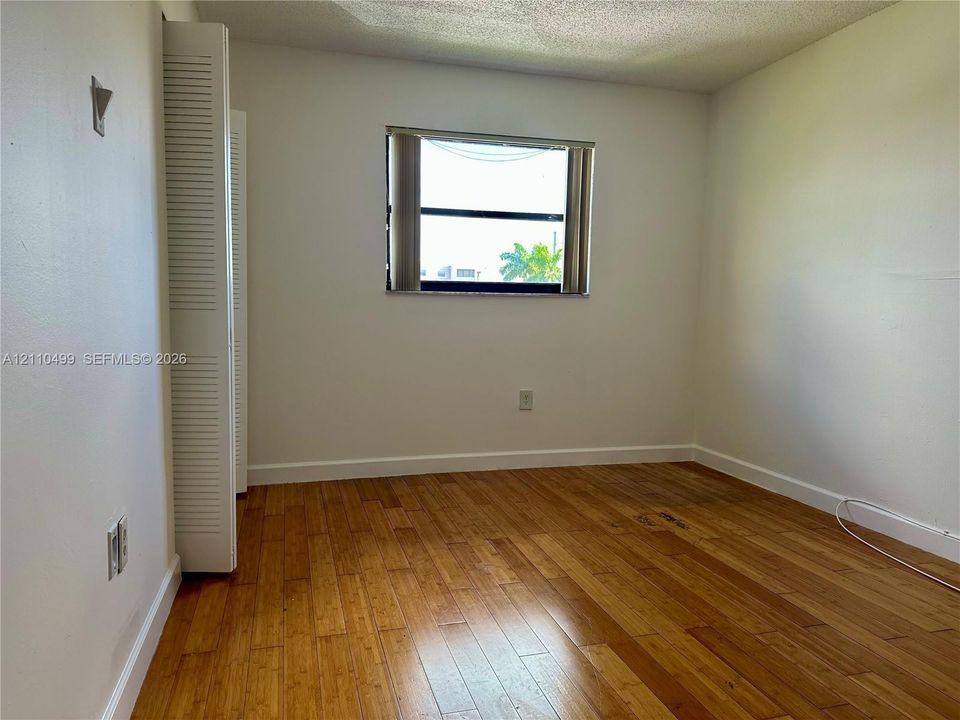 Interior room featuring wood-finish flooring, a horizontal sliding window, and a built-in closet with louvered doors