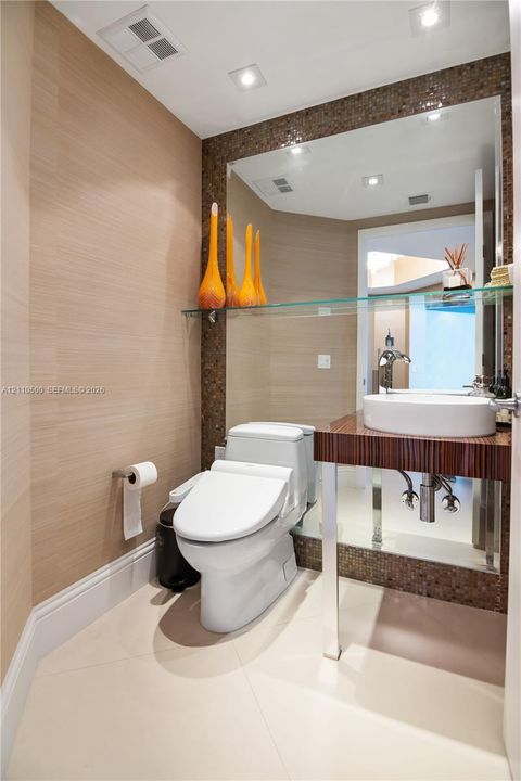 Floating vanity with a circular vessel sink, wall-mounted faucet, textured wallpaper, mosaic tile backsplash, and large-format floor tile