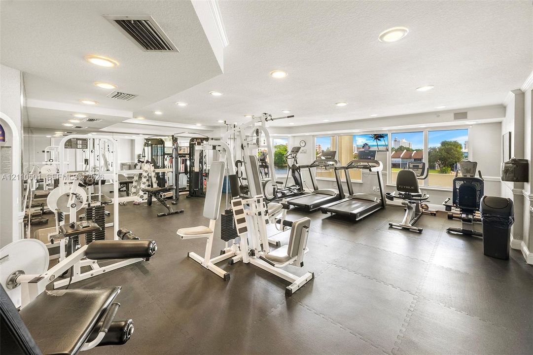 Fitness room featuring a mirrored wall, recessed lighting, rubberized flooring, and large windows