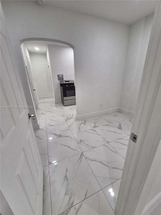 Polished white floor tile with gray veining, arched entryway, and stainless steel freestanding oven