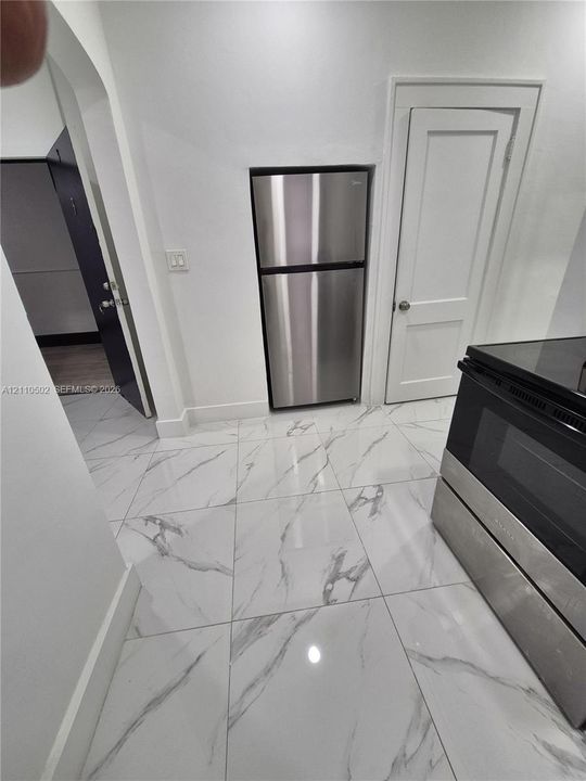 Kitchen featuring large-format tile flooring with a veined pattern, stainless steel refrigerator, and built-in stainless steel oven