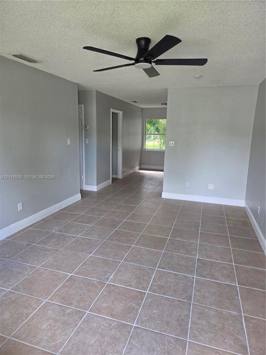 Large-format tile flooring, matte black ceiling fan, and neutral wall tones