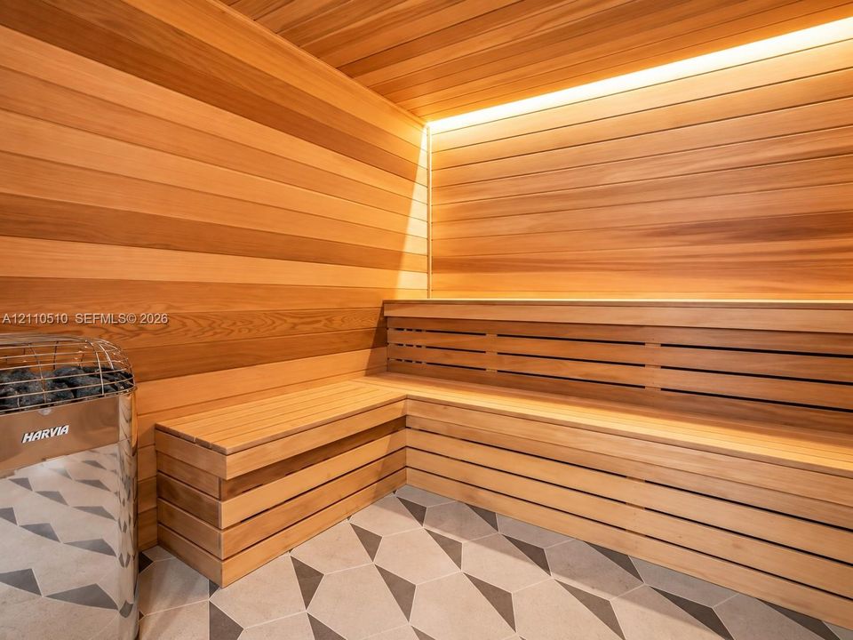 Sauna featuring wood-plank walls and ceiling, integrated multi-level bench seating, a chrome-finish Harvia heater, and geometric-pattern floor tile with recessed linear accent lighting