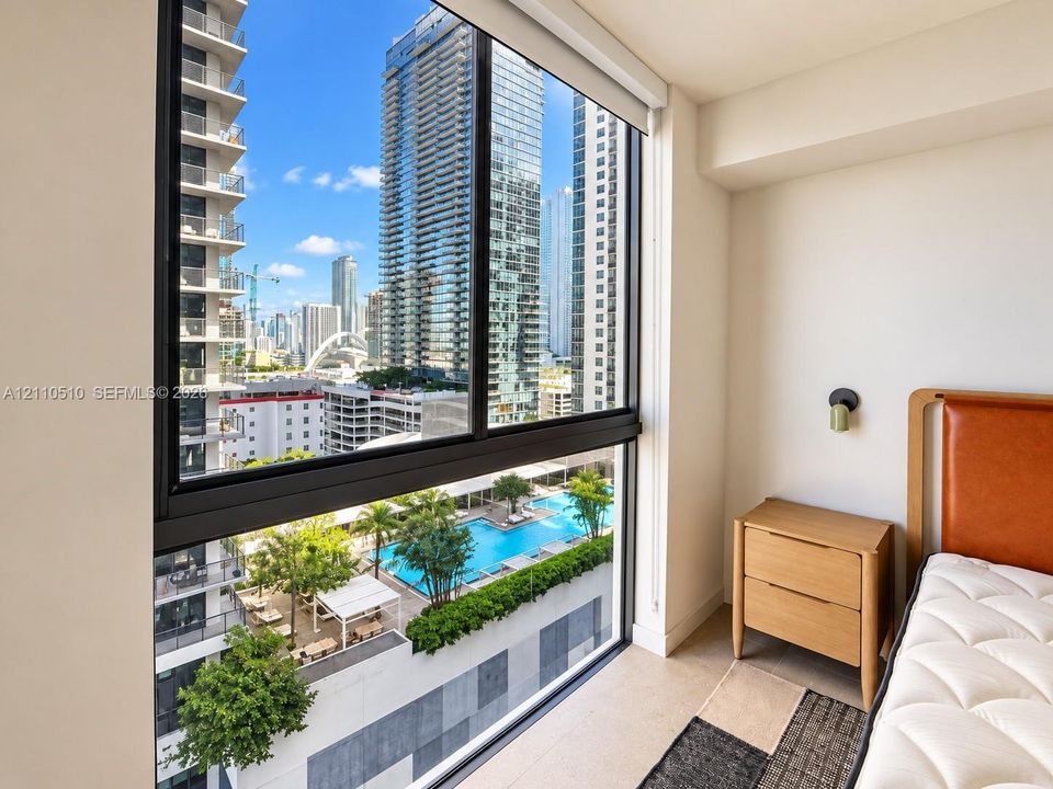 Floor-to-ceiling windows featuring black framing and motorized roller shades, showcasing expansive metropolitan scenery