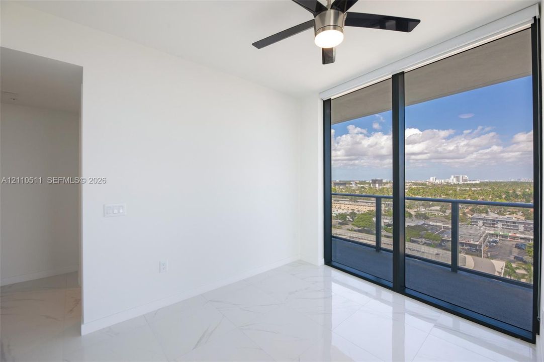 Second bedroom, floor-to-ceiling windows, high-gloss stone-finish flooring, private balcony with metal railing, and integrated ceiling fan with lighting