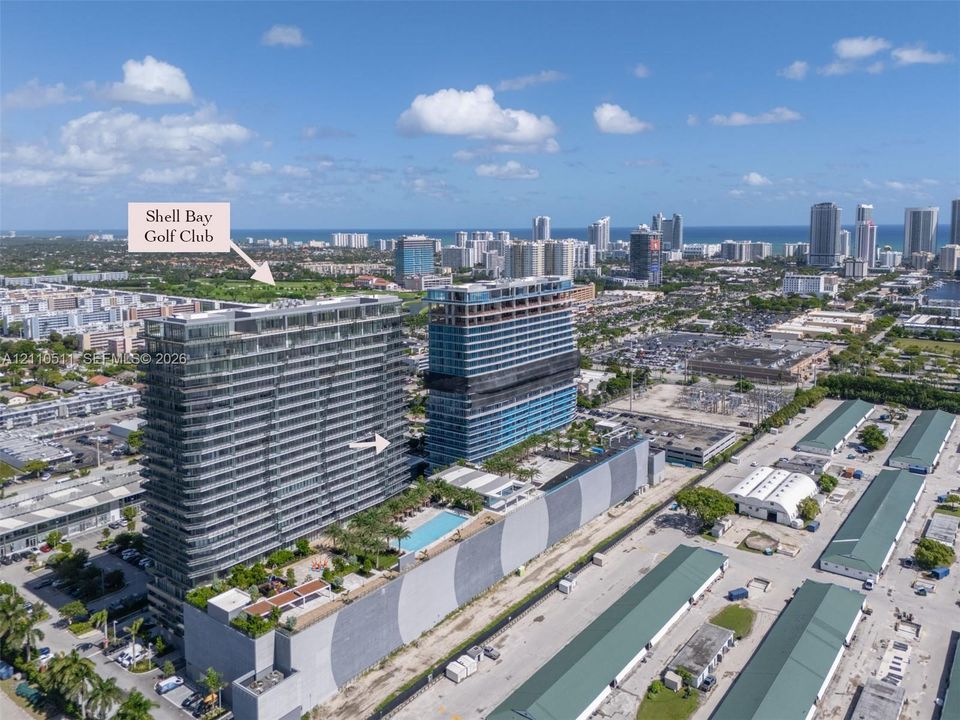Aerial perspective of high-rise condominium architecture featuring glass-panel balconies, a ground-level swimming pool, and a landscaped sun deck