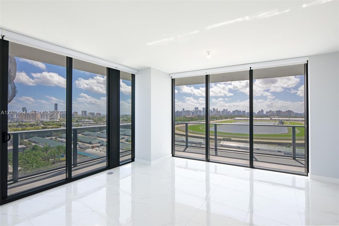 Floor-to-ceiling glass walls, expansive private balcony with metal railing, high-gloss tile flooring, and open-plan interior