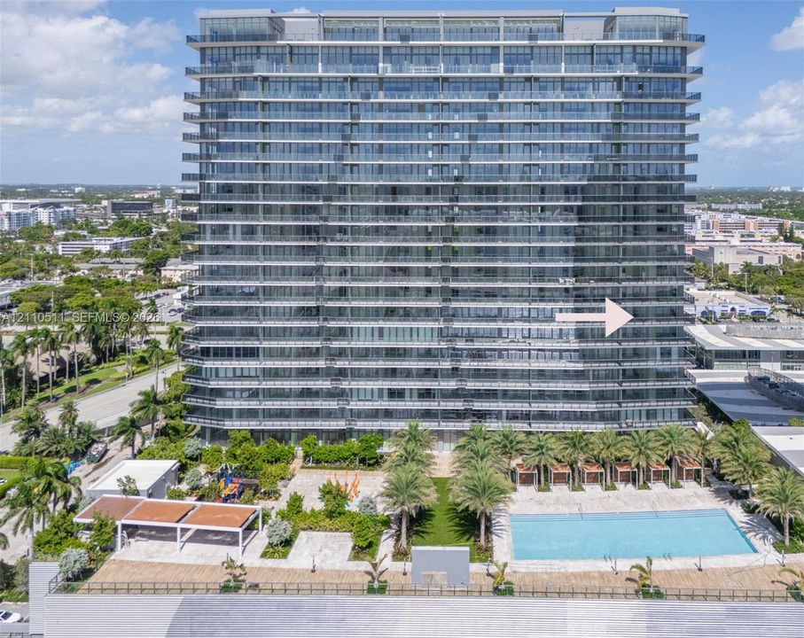 High-rise architectural exterior featuring glass-paneled balconies, a ground-level swimming pool, hardscaped patio, integrated landscaping, and covered cabanas
