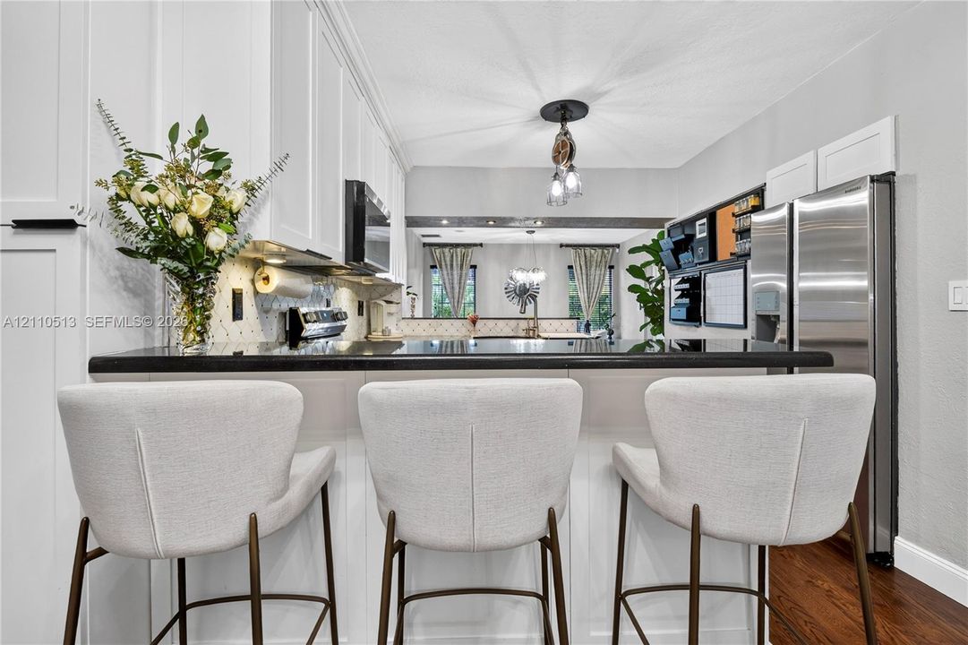 Kitchen featuring white shaker-style cabinetry, dark stone countertops, stainless steel appliances, and wood-finish flooring
