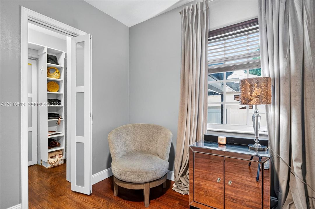 Wood-finish flooring, white framed multi-panel door, and custom built-in shelving unit