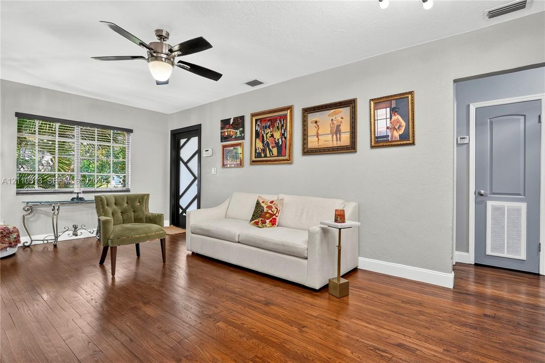 Living area featuring wood-finish flooring, a multi-pane glass entry door, and a central ceiling fan
