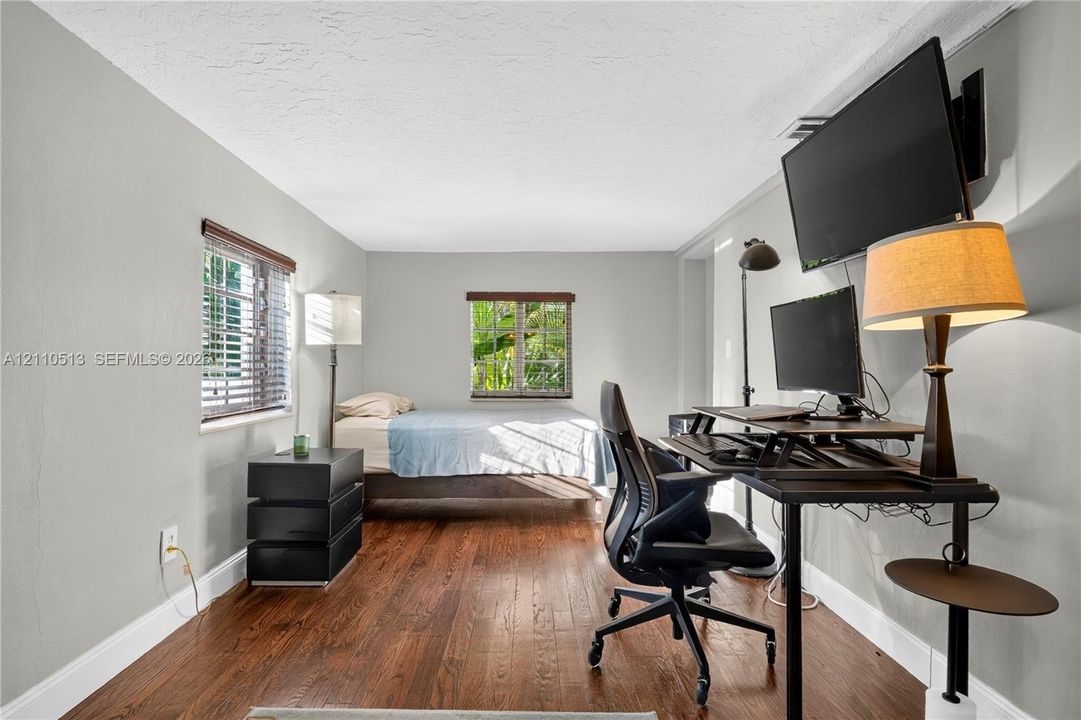 Interior room featuring wood-finish flooring, neutral walls, and two windows with horizontal blinds