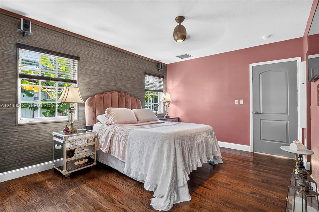 Room featuring wood-finish flooring, dual windows with blinds, a textured accent wall, and a contemporary ceiling-mounted light fixture
