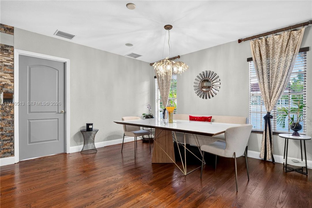 Wood-finish flooring, multi-faceted crystal pendant lighting, stacked-stone accent wall, and arch-top door