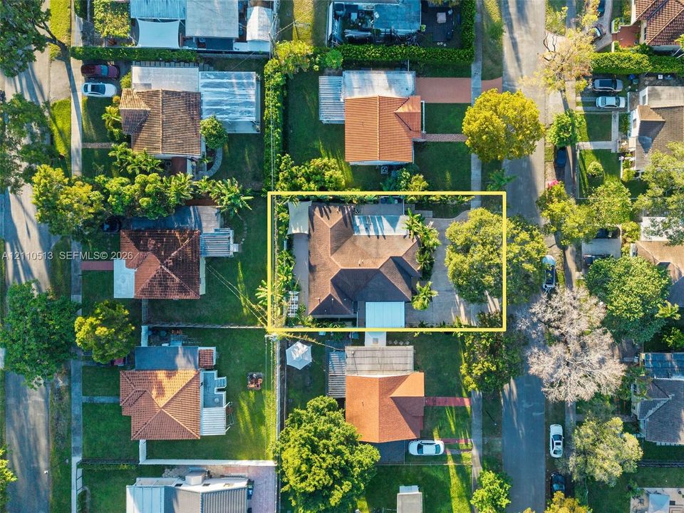 Aerial perspective of a property featuring a multi-pitched roof, concrete driveway, established trees, and perimeter landscaping within a residential neighborhood